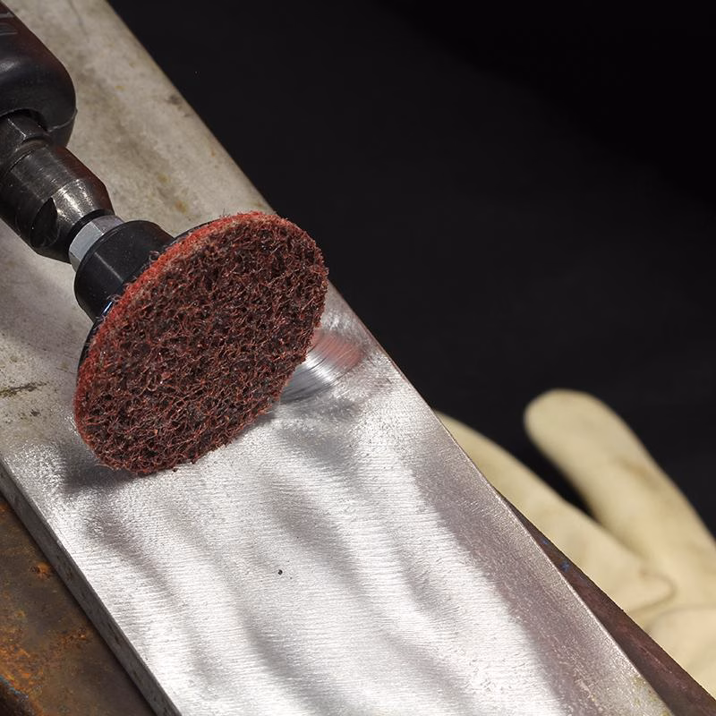 GSP50C_4 - Alpha Tools Rotary tool with a red abrasive disc grinding a metal edge, with a gloved hand in the background,